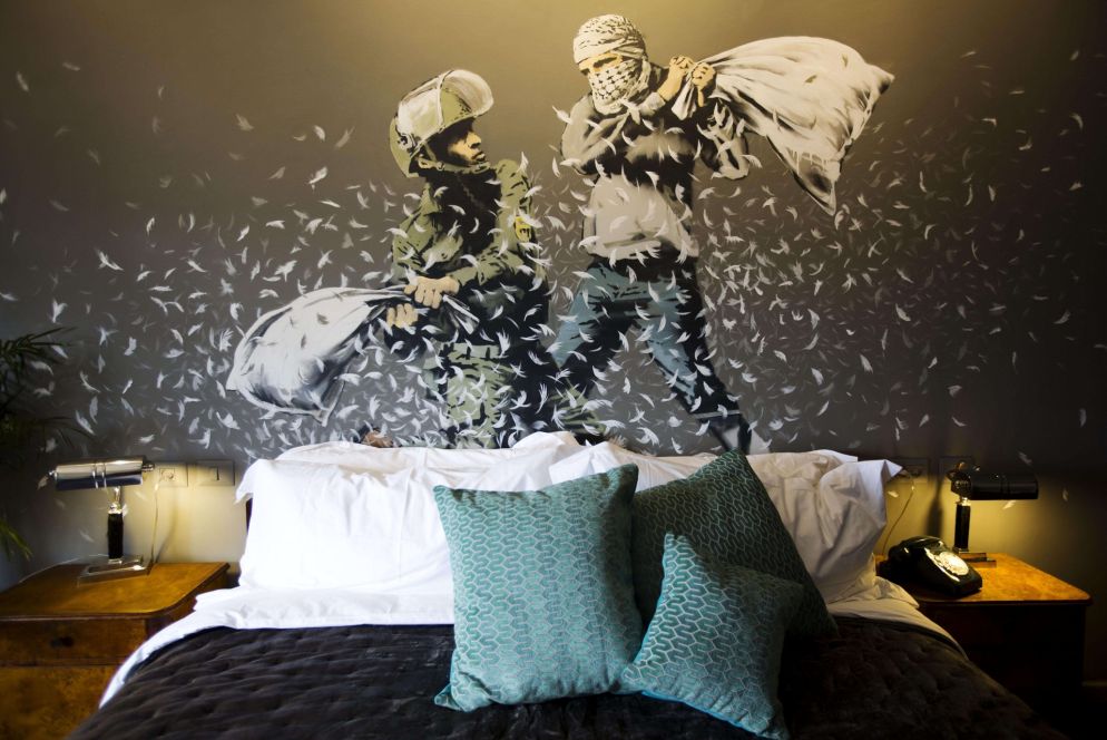 Banksy, un poliziotto israeliano e un palestinese si prendono a cuscinate in una delle sale del The Walled Off Hotel nella città di Betlemme