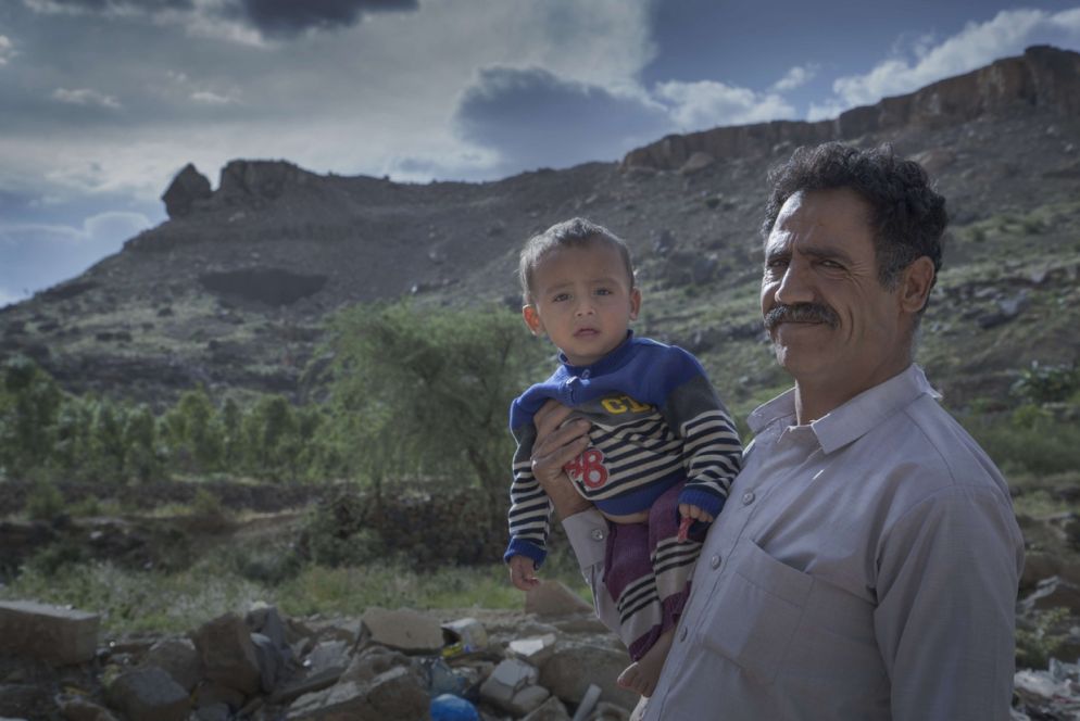 Un padre sfollato tiene il figlioletto in braccio, dargli da mangiare è un'impresa (Oxfam - Gabreez)