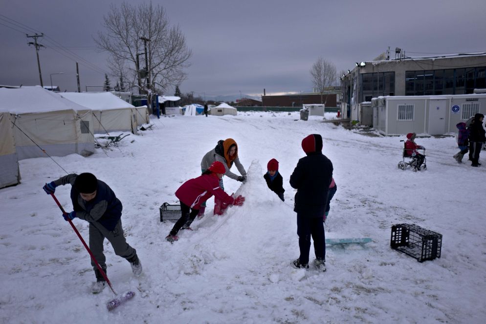 Dei bambini afghani nel campo greco di Oinofyta a 58 chilometri da Atene, in Grecia, sono intenti a costruire un pupazzo di neve. Foto: Muhammed Muheisen/Ansa