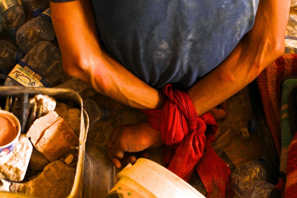 Un prigioniero di Daesh è legato con le mani dietro la schiena nella prigione improvvisata nell’avamposto delle forze speciali irachene