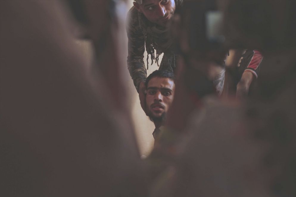 Uno dei tenenti della brigata costringe un prigioniero di Daesh a mostrare il volto ai giornalisti