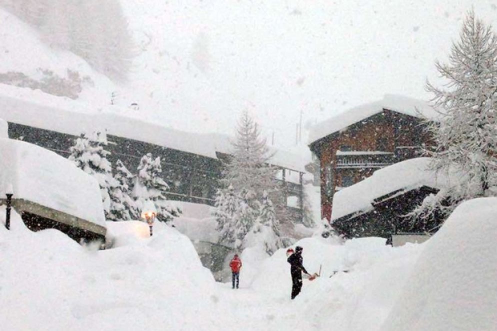 Alcuni turisti si fanno largo tra la neve spalando. La mole di quella caduta sulle case e sulle strade è impressionante