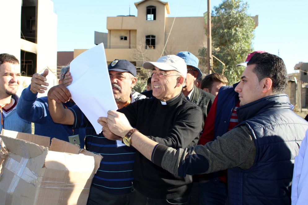 Don Georges con i suoi fedeli a Qaraqosh studia la mappa con le case