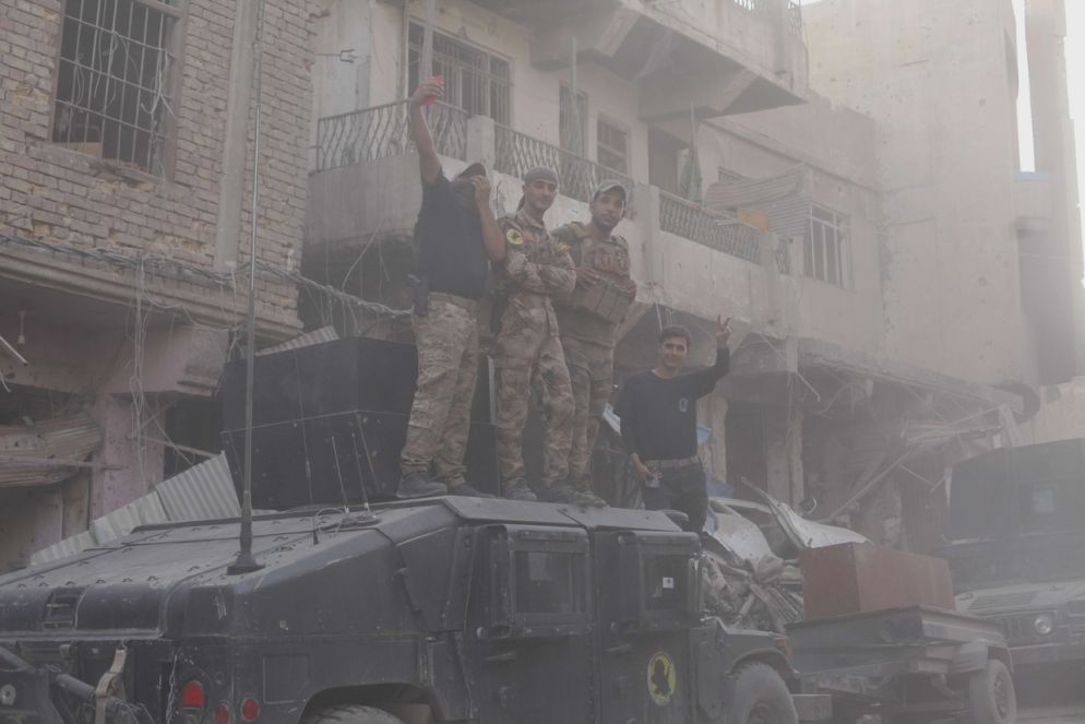 Soldati iracheni posano su un carro armato e scattano selfie mentre si solleva la polvere delle macerie della città vecchia di Mosul