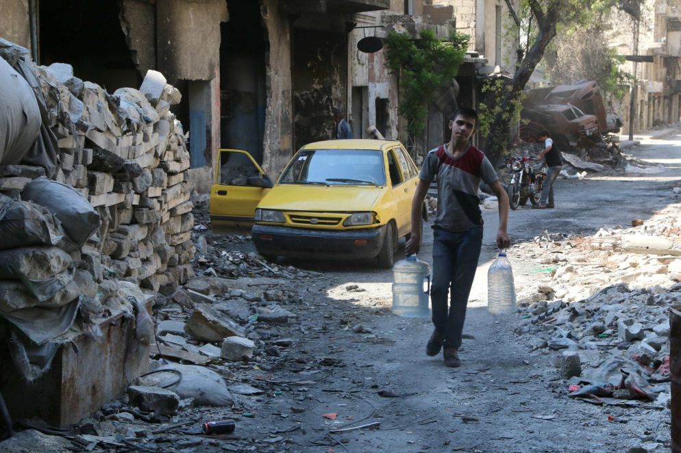 Un ragazzo si rifornisce di acqua ad Aleppo (Reuters)