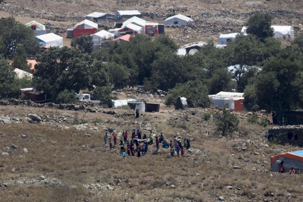 Alcuni siriani si allontano dalle casupole dove si erano rifugiati. Le bombe si avvicinani (Ansa)
