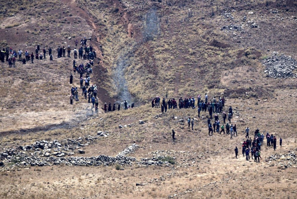 Un gruppo di siriani in fuga si avvicinano alle postazioni israeliane sulle alture del Golan chiedendo aiuto (Ansa)