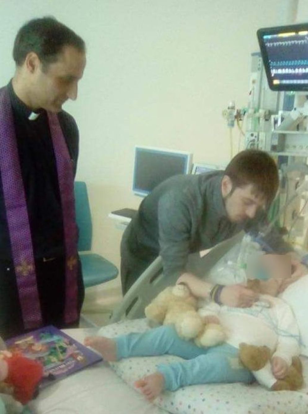 Alfie con il padre e il sacerdote in ospedale