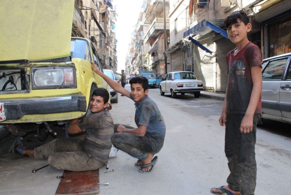 Dei ragazzi riparano un'auto per strada nel quartiere Midan, Aleppo Ovest