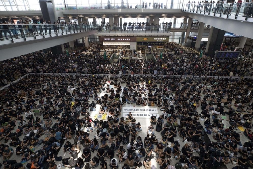L'aeroporto di Hong Kong occupato dai manifestanti. Un occhio coperto in segno di solidarietà con un manifestante ferito (Ansa)