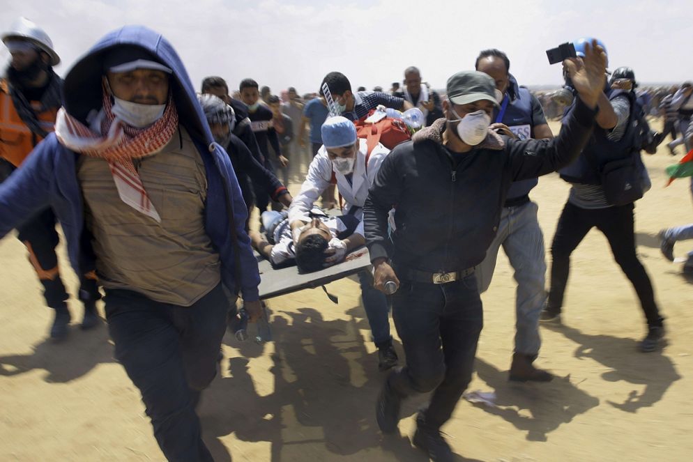 Medici e dimostranti trasportano un giovane ferito a est di Khan Younis, nella Striscia di Gaza (Ansa)