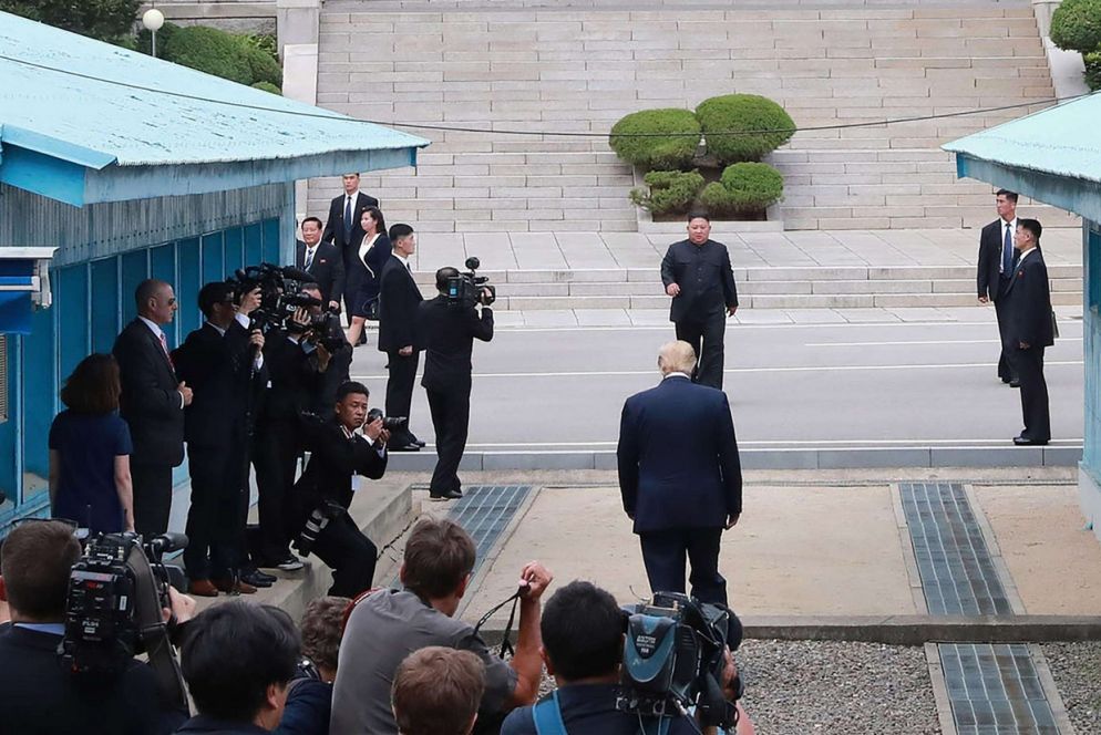 Trump e Kim camminano uno incontro all'altro, a cavallo della linea di confine (Ansa)