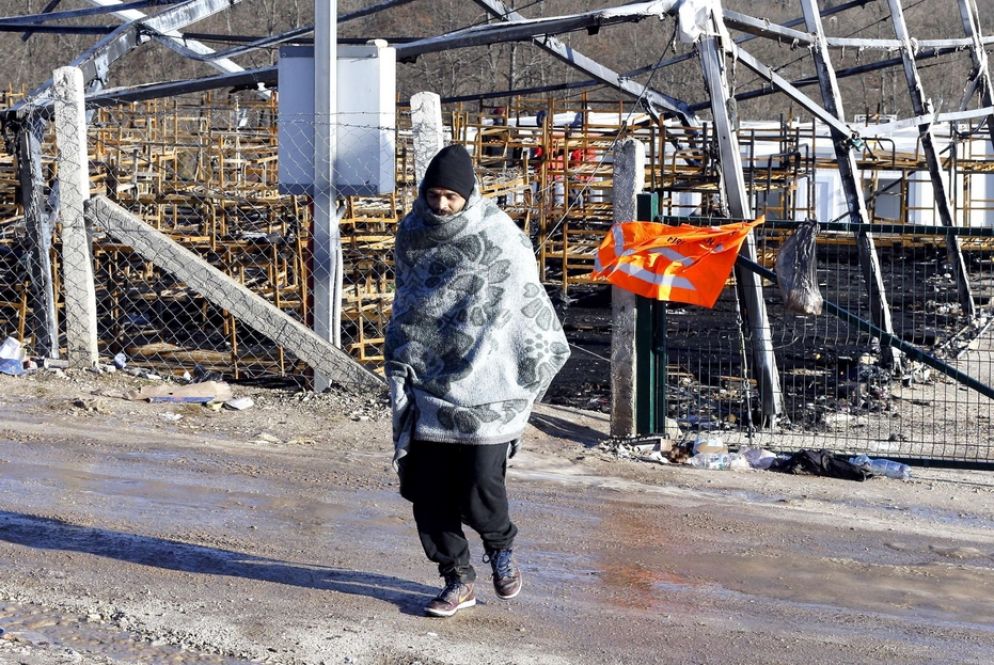 Un uomo davanti a quel che resta del campo di Lipa, bruciato nell'incendio del 23 dicembre