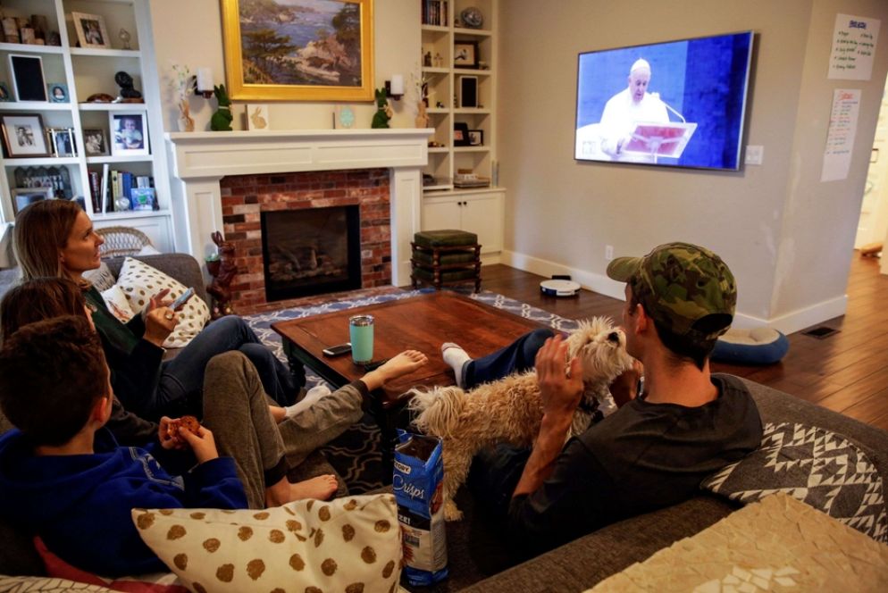 Una famiglia mentre segue in diretta tv la preghiera e la benedizione Urbi et Orbi di papa Francesco - Reuters