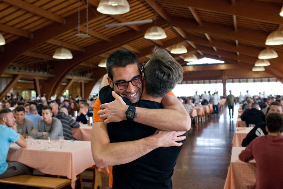 Un abbraccio, prima dell'avvento del Covid, tra due ragazzi nel grande salone della comunità riminese di San Patrignano
