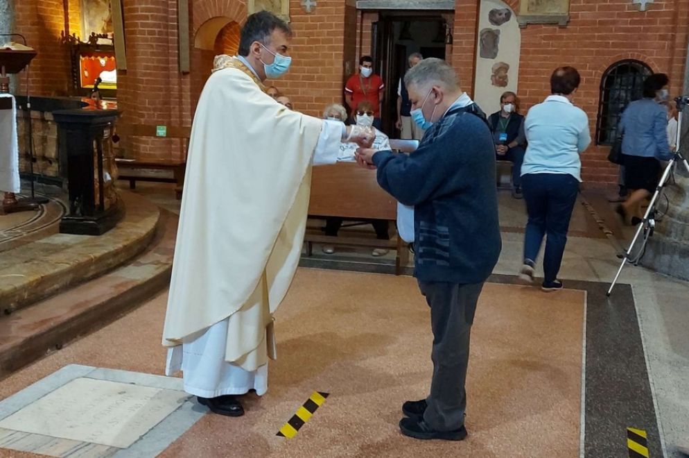 Don Franco Amati, parroco di Santa Maria Rossa nella periferia di Milano, è stato in fin di vita per il Covid. Nella foto mentre dà la Comunione a un fedele, contagiato e ormai guarito - Avvenire - Avvenire