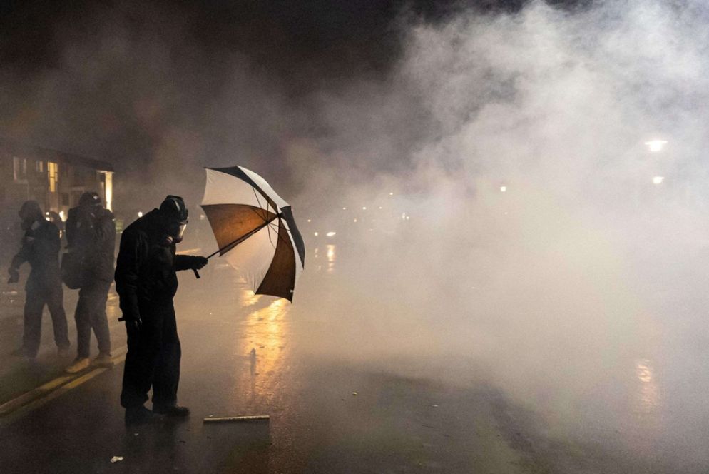 Un manifestante si ripara dai gas lacrimogeni sparati dalla polizia - Ansa