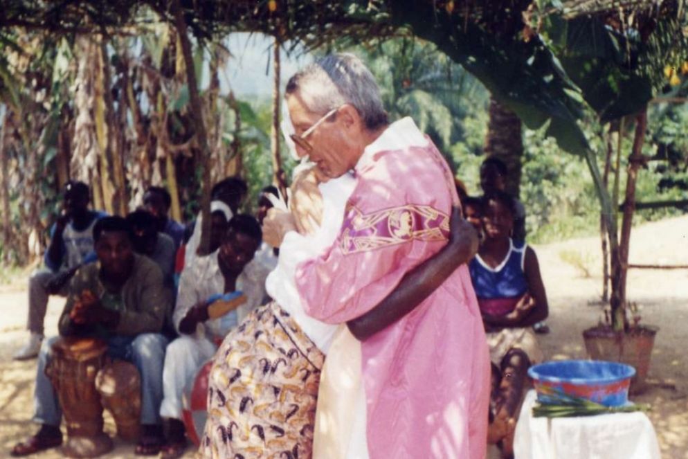padre Pierino Zoni, mentre abbraccia una donna africana. - .