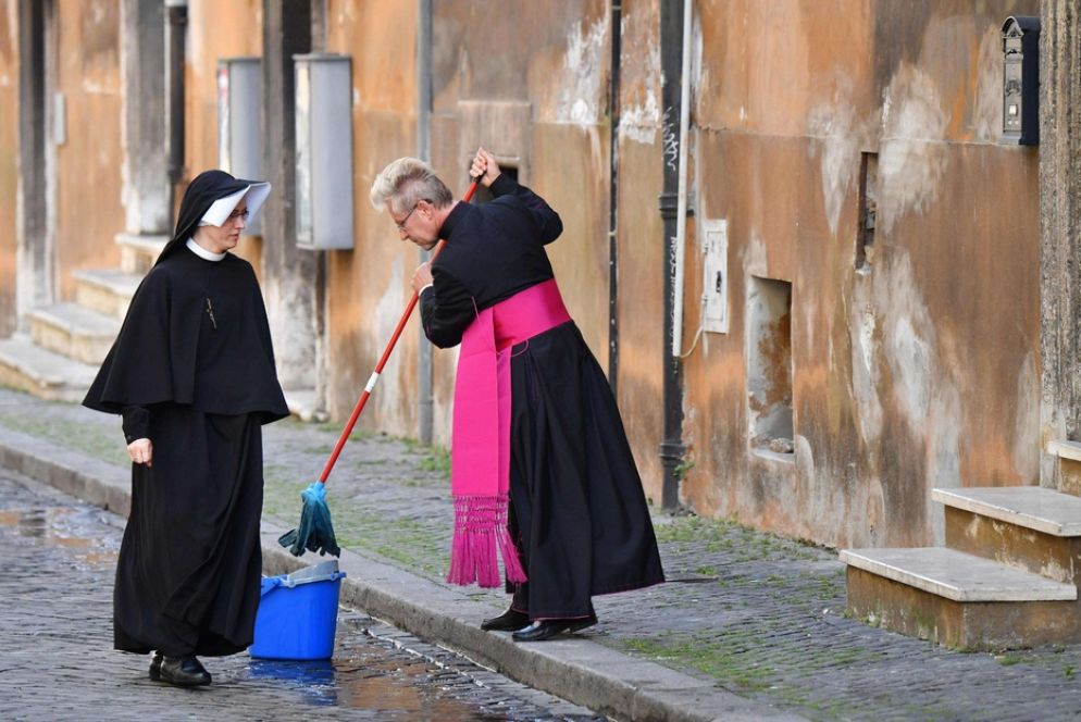 Il vescovo Josef Bart pulisce la strada in fronte al Santuario di Santo Spirito in Sassia - Ansa