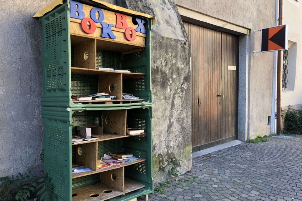 Cassette di plastica di recupero disposte a formare una piccola scaffalatura in una via di Merano