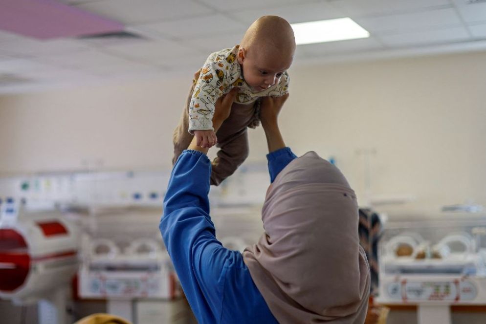 Un'infermiera gioca con Yehia, solo loro ora a prendersi cura di lui. Amal Abu Khatla, che lavora nell'ospedale, ha raccontato che le condizioni di Yehia erano gravi quando è arrivato dal nord di Gaza: «Dopo una settimana, grazie a Dio, la sua salute è migliorata, ma abbiamo perso i contatti con i suoi genitori, al punto che pensavamo che i genitori fossero stati uccisi».