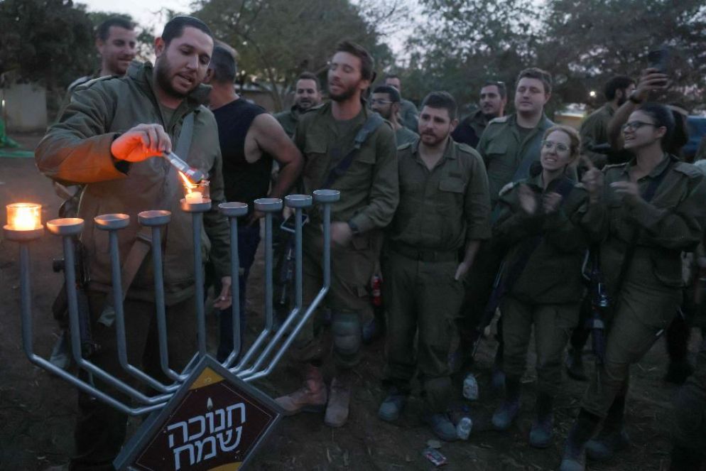Un soldato accende la prima luce di Hanukkah in una postazione militare sul fronte di Gaza - ANSA