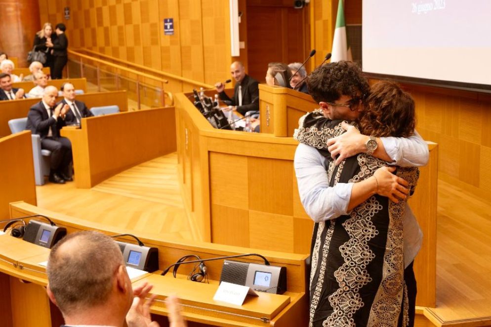 Madre e figlio si abbracciano dopo una testimonianza, tra gli applausi della platea - Ansa