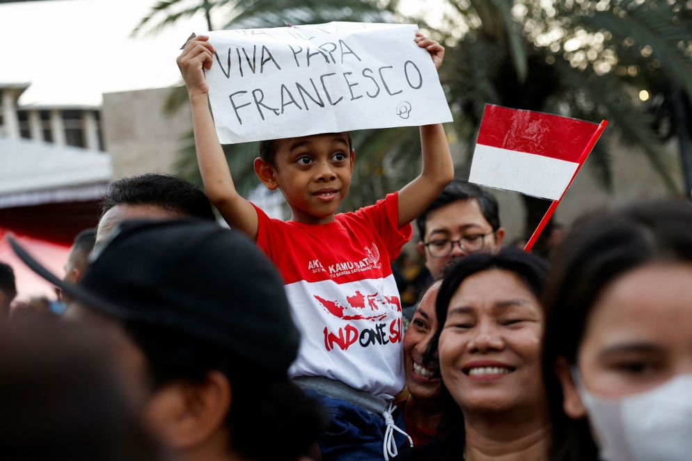 Un bambino innalza uno striscione di benvenuto per il Papa - Reuters