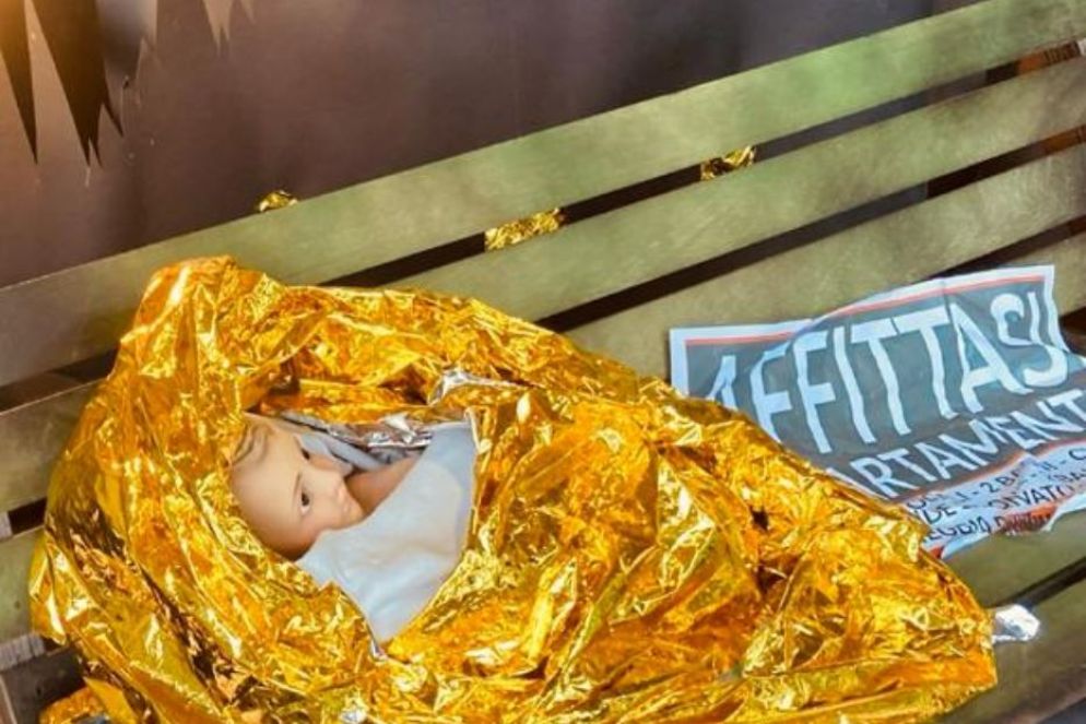 Il Bambino Gesù avvolto in un telo termico e deposto su una panchina, nel presepe di Casa della Carità - .