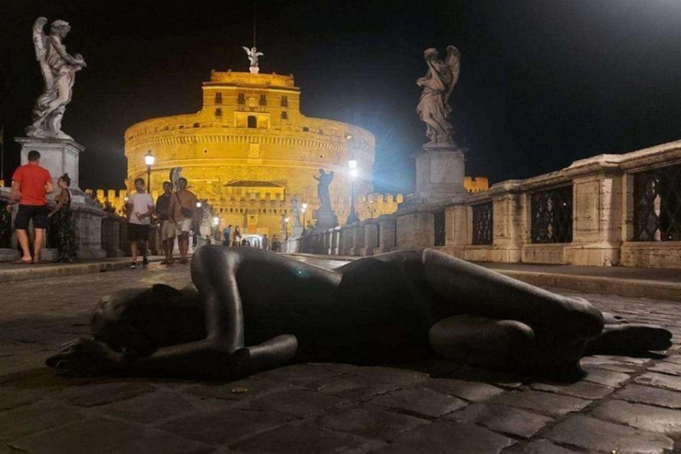 La statua del giovane migrante prostrato con lo sfondo di Castel Sat'Angelo - Foto Liverani