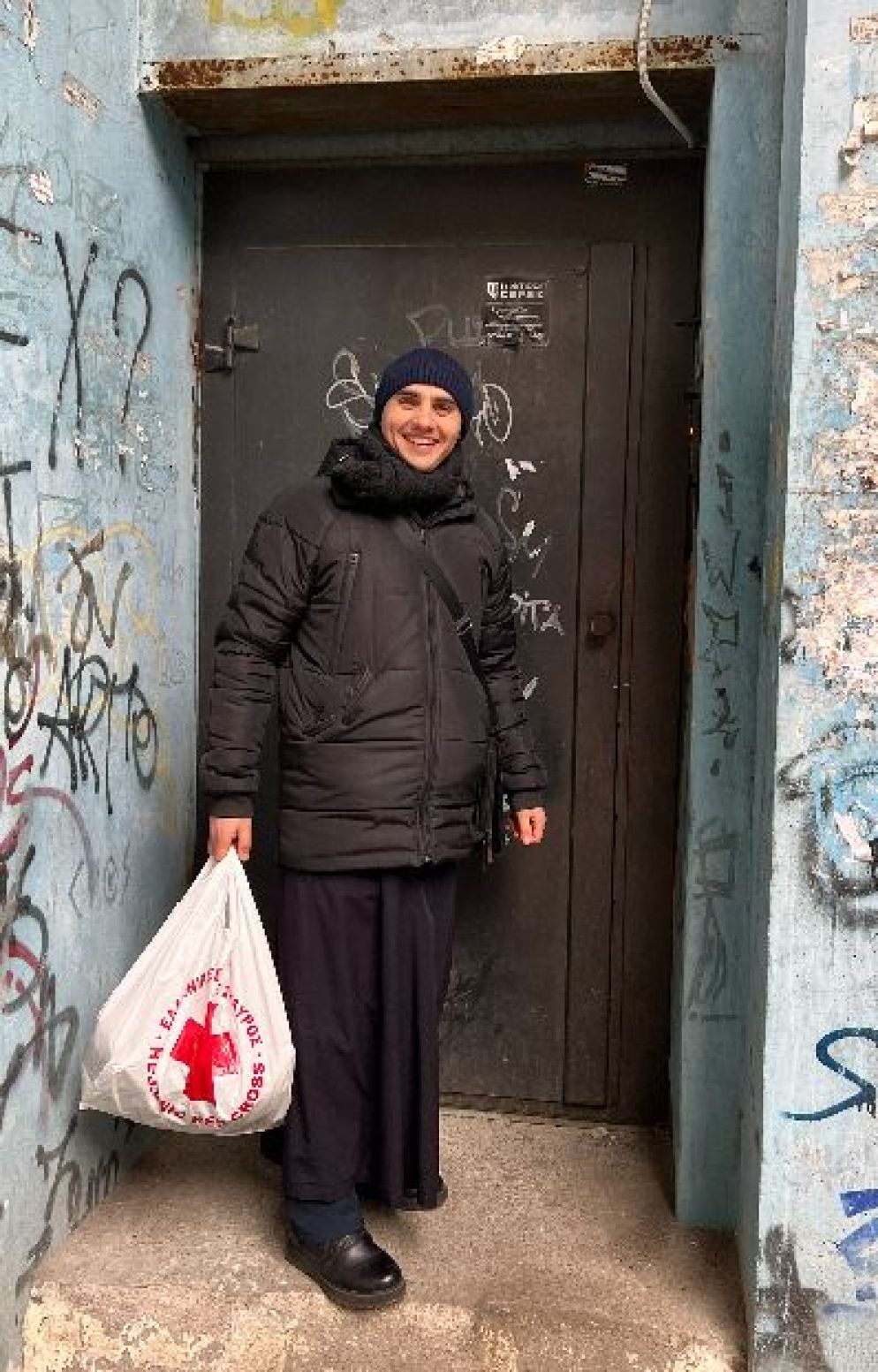 Padre Oleksandr Bogomaz all'ingresso del condominio di Zaporizhzhia dove vive da sfollato - Gambassi