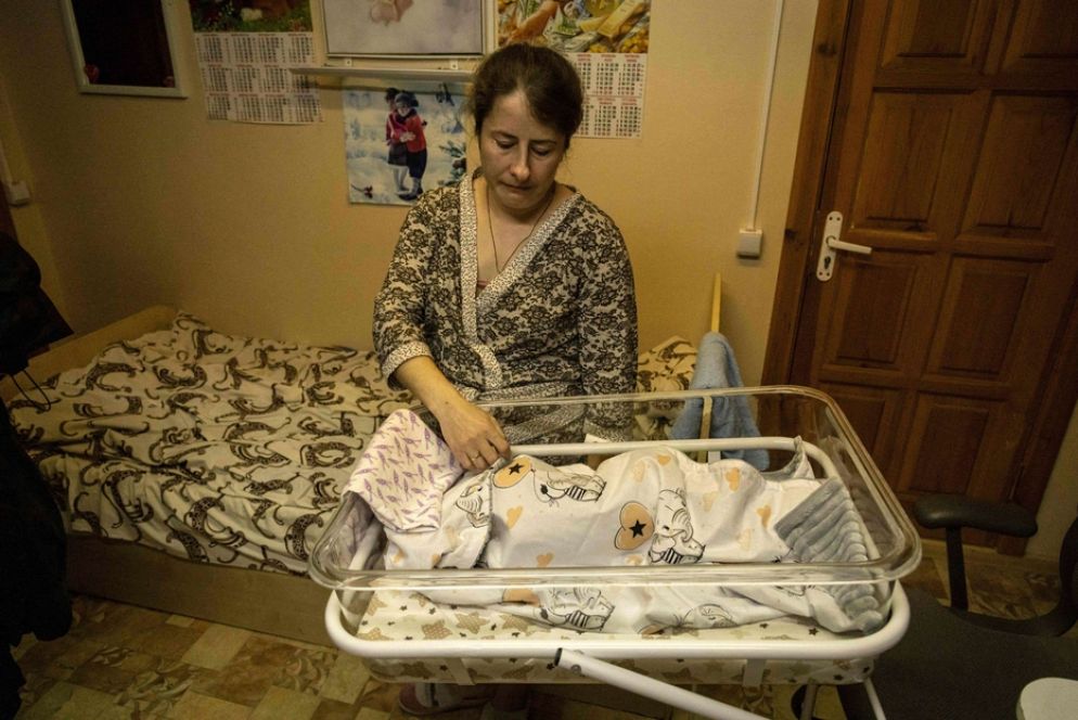 Una mamma in un rifugio veglia il suo bebè in una città ucraina