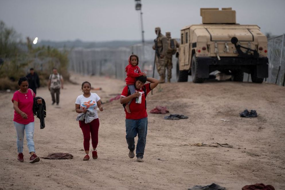 Agenti sorvegliano le persone richiedenbti asilo sulla riva del Rio Bracvo - Reuters