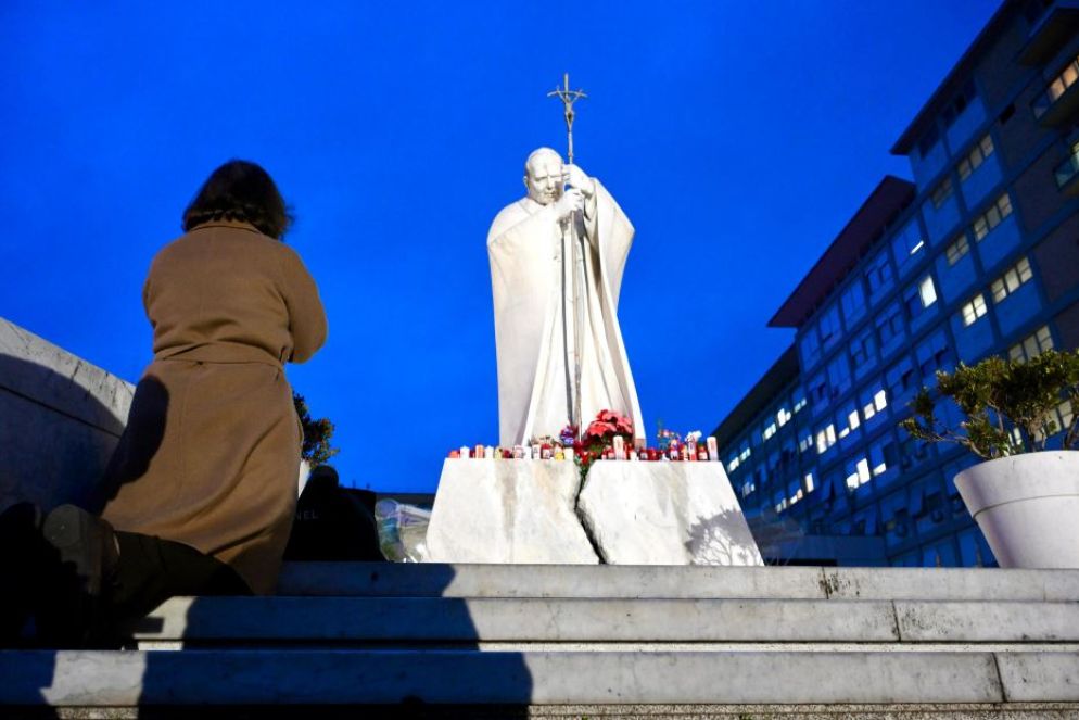 C'è chi si ferma a pregare lungamente, in ginocchio, davanti alla statua di Giovanni Paolo II al Gemelli - Ansa