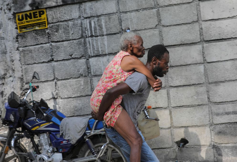 Un giovane cerca di portare via dalla zone degli scontri l'anziana madre - Reuters