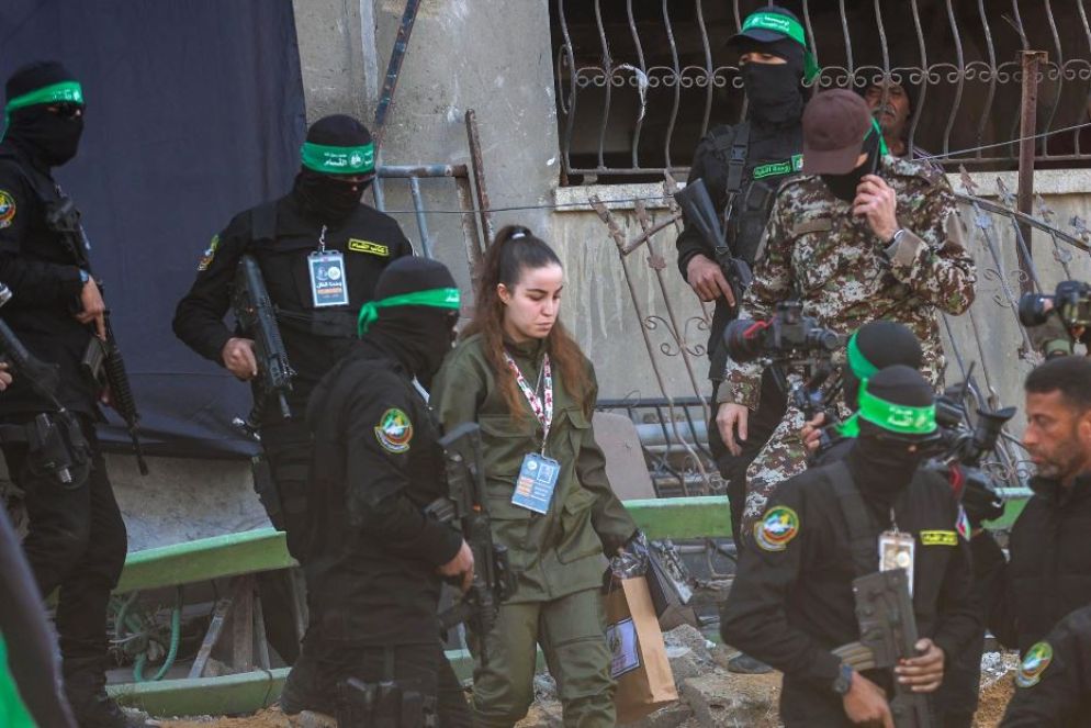 La soldata Agam Berger tra i miliziani pochi momenti prima della consegna alla Croce Rossa - Ansa