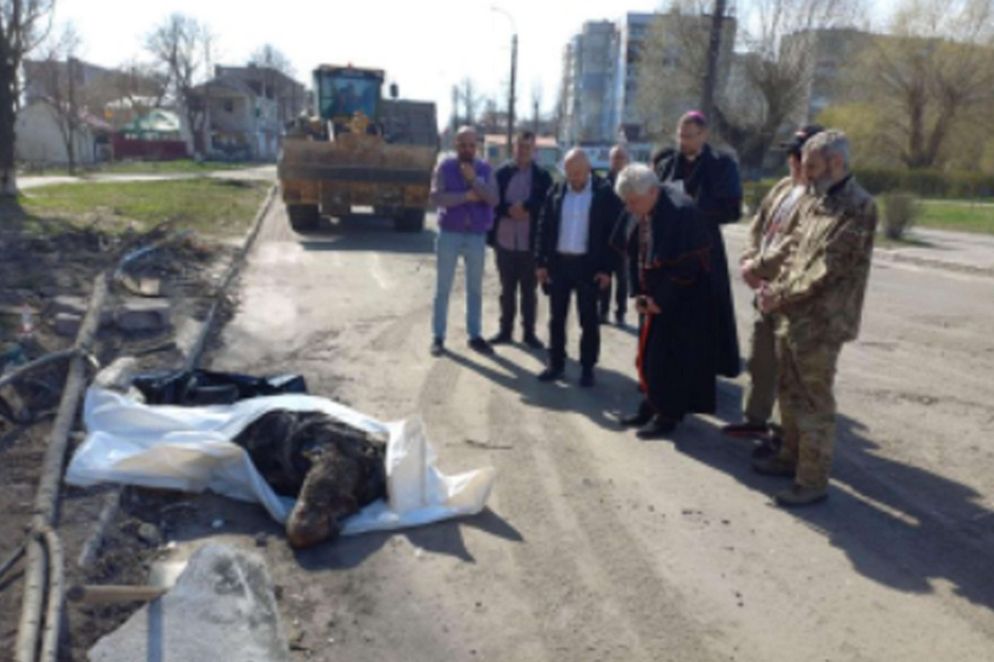 Il cardinale Konrad Krajewski di fronte al corpo recuperato di una vittima del massacro di Bucha - Ansa Twitter