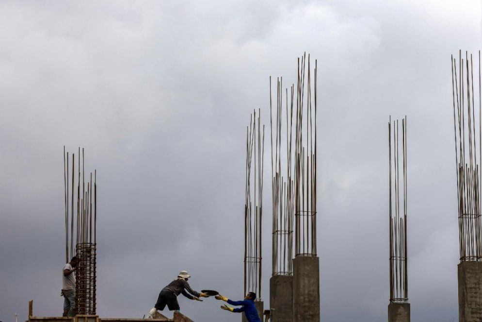 Operai edili al lavoro sotto la pioggia in un cantiere di Kathmandu - ANSA