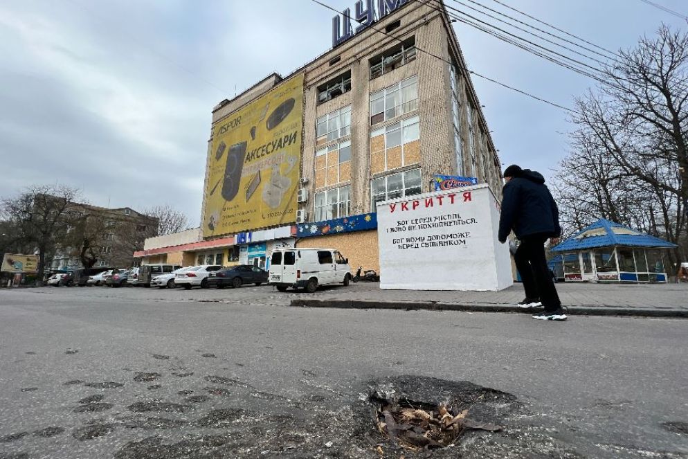 Il cratere sulla strada a tre settimane dalla strage davanti al supermercato nel centro di Kherson - Gambassi