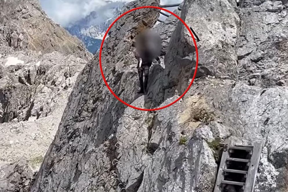 Il turista fotografato in Trentino mentre scende da una via ferrata con un bambino piccolo in braccio - Ansa